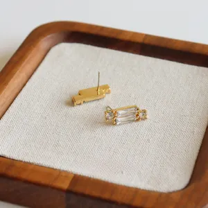 Detailansicht goldener Quastenohrringe mit Zirkonsteinen auf einem Leinendispaly