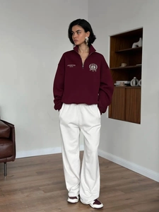 Detailed view of burgundy quarter-zip sweatshirt with white assertive unity embroidery