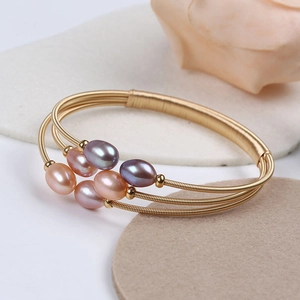 Macro detail of adjustable gold-wrapped wire bracelet with multi-color freshwater pearls