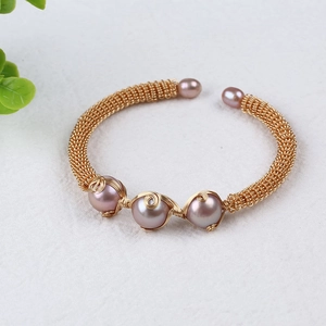 Detail of hand-woven gold-filled cuff bracelet featuring five pink freshwater pearls