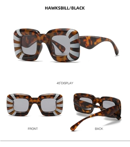 Detail view of square hawksbill sunglasses with white radial stripes and dark lenses