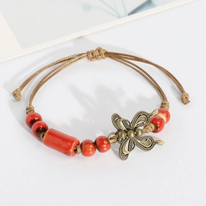 Ethnic ceramic bracelet with red beads, bronze butterfly charm, and woven brown cord