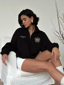 Women's black half-zip sweatshirt with Assertive Unity print and gold emblem