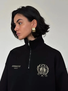 Detail of the high collar quarter-zip closure and assertive unity shield embroidery