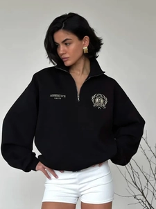 Close-up of black half-zip polo sweatshirt featuring college-style badge and lettering