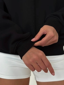 Detail showing elastic ribbed cuffs on a black long-sleeved polo hoodie for women