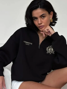 Detail of embroidered crest and Assertive Unity text on black half-zip sweatshirt