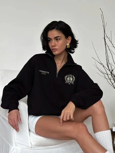 Detail of black half-zip sweatshirt with chest logo and silver metal zipper