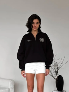 Detail of black half-zip polo sweatshirt with shield embroidery and assertive unity text