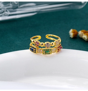 Close-up of gold layered open ring with vibrant multi-color zircon stones on dark fabric