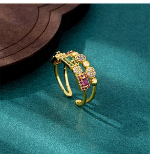 Detail view of gold geometric open ring with colorful zircon stones on green velvet