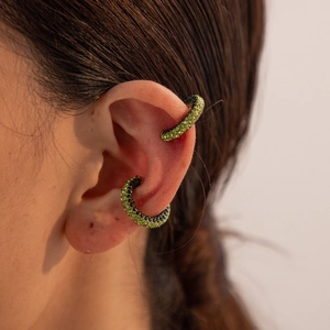 Close-up of a pair of gold ear cuffs encrusted with sparkling green cubic zirconia