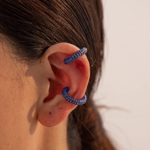Detail view of gold C-shaped ear cuffs with micro-paved royal blue cubic zirconia