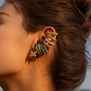 Detail of colorful cubic zirconia ear cuffs and golden star earring on model ear
