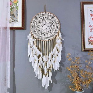 Large white bohemian dream catcher with feathers and wooden beads on a grey wall