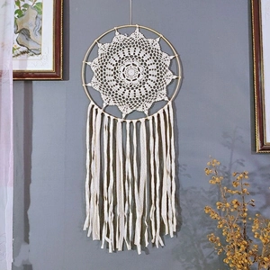 Detail of bohemian white crochet wall hanging with intricate mandala lace and long tassels