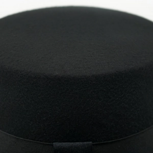 Close-up of black wool felt flat top hat featuring a detailed black grosgrain ribbon trim