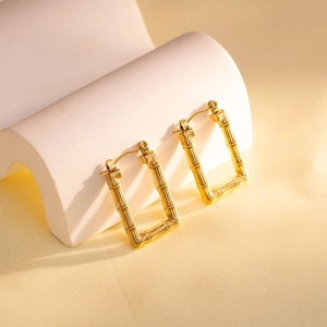Macro detail of gold geometric earrings with textured bamboo pattern and secure buckle