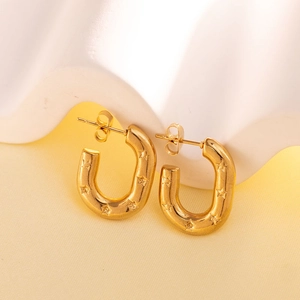 Detail of gold U-shaped earrings featuring textured 3D star patterns and glossy finish