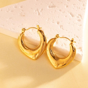 Detailed macro view of gold-plated U-shaped earrings with unique hammered metal texture