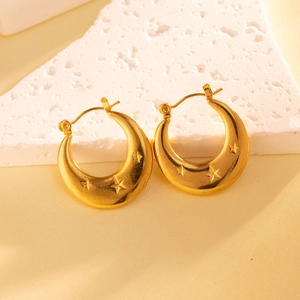 Macro shot of gold crescent moon earrings with star pattern on white stone base