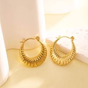 Macro detail of gold-plated stainless steel earrings with wavy textured ripple design