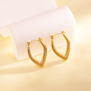 Close-up of gold V-shaped huggie earrings featuring textured horizontal ribbing details