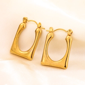 Detail of gold U-shaped geometric earrings with polished finish on silk background