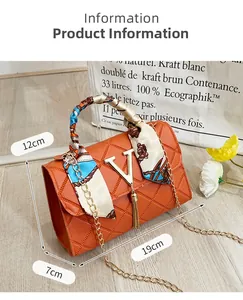 Detail of orange quilted handbag with gold V logo, tassel, and silk scarf handle wrap
