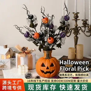 Macro view of Halloween decoration featuring purple eyeballs and pumpkin branch on a black base