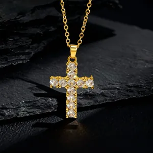 Close-up of a gold cross pendant necklace with sparkling cubic zirconia on dark stone