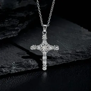 Macro shot of silver cross pendant with sparkling zircons on a dark textured stone