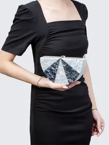 Detail of a semicircular marble pattern acrylic clutch bag with a gold metal lock