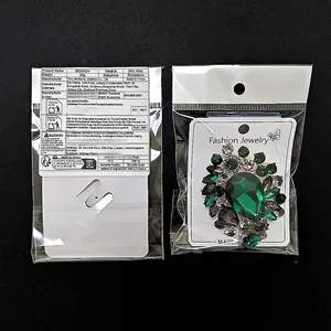 Makroaufnahme einer dunkelgrünen Strassbrosche in Verpackung auf schwarzem Grund