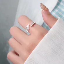 Detail of silver paper plane ring with zircon accents and adjustable knotted band