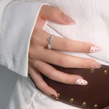 Close-up of a silver knotted bow ring with small diamonds on a model's finger