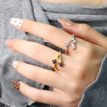 Detail view of adjustable floral rings in gold and silver with blue and white stones