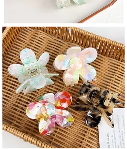 Macro shot of assorted floral acetate hair claws in a woven basket with diverse textures