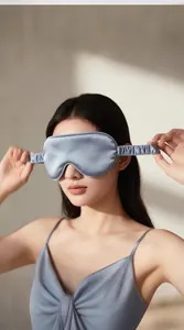 Close-up of a grey-blue silk sleep mask with elastic strap worn by a female model