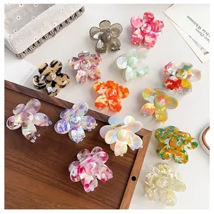 Detailed top view of colorful acetate flower hair claws arranged on a minimalist background