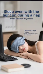Detail of wide grey-blue silk sleep mask showing light-blocking fit on a resting woman