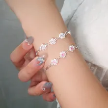 Detail of elegant silver and pink flower charm bracelets on a woman's wrist