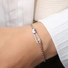 Detailed view of a silver heart safety pin bracelet worn on wrist for a romantic style