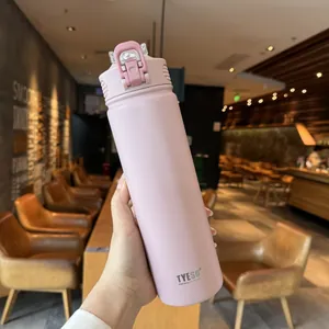 Close-up of pink matte TYESO vacuum flask with a secure flip-top lid being held in a cafe