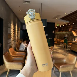 Close-up of matte yellow insulated tumbler with carry handle in a cozy cafe setting