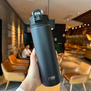 Close-up of black matte stainless steel vacuum flask with handle lid in a cafe setting