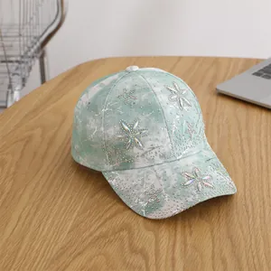 Detail of mint green tie-dye baseball cap with sparkling rhinestone flower embellishments