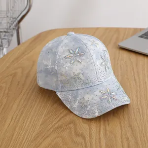 Close-up of acid wash denim baseball cap with sunflower rhinestones on wooden table