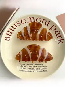 Detailed view of two croissant hair claws with small white rhinestones on a ceramic plate