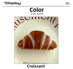 Detail showing crystal-embellished croissant hair claw clip on a white decorative plate